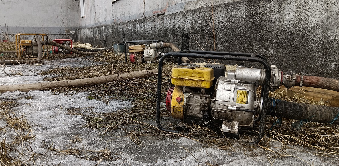 Откачка мотопомпами талой воды из подвала дома в Архангельской области